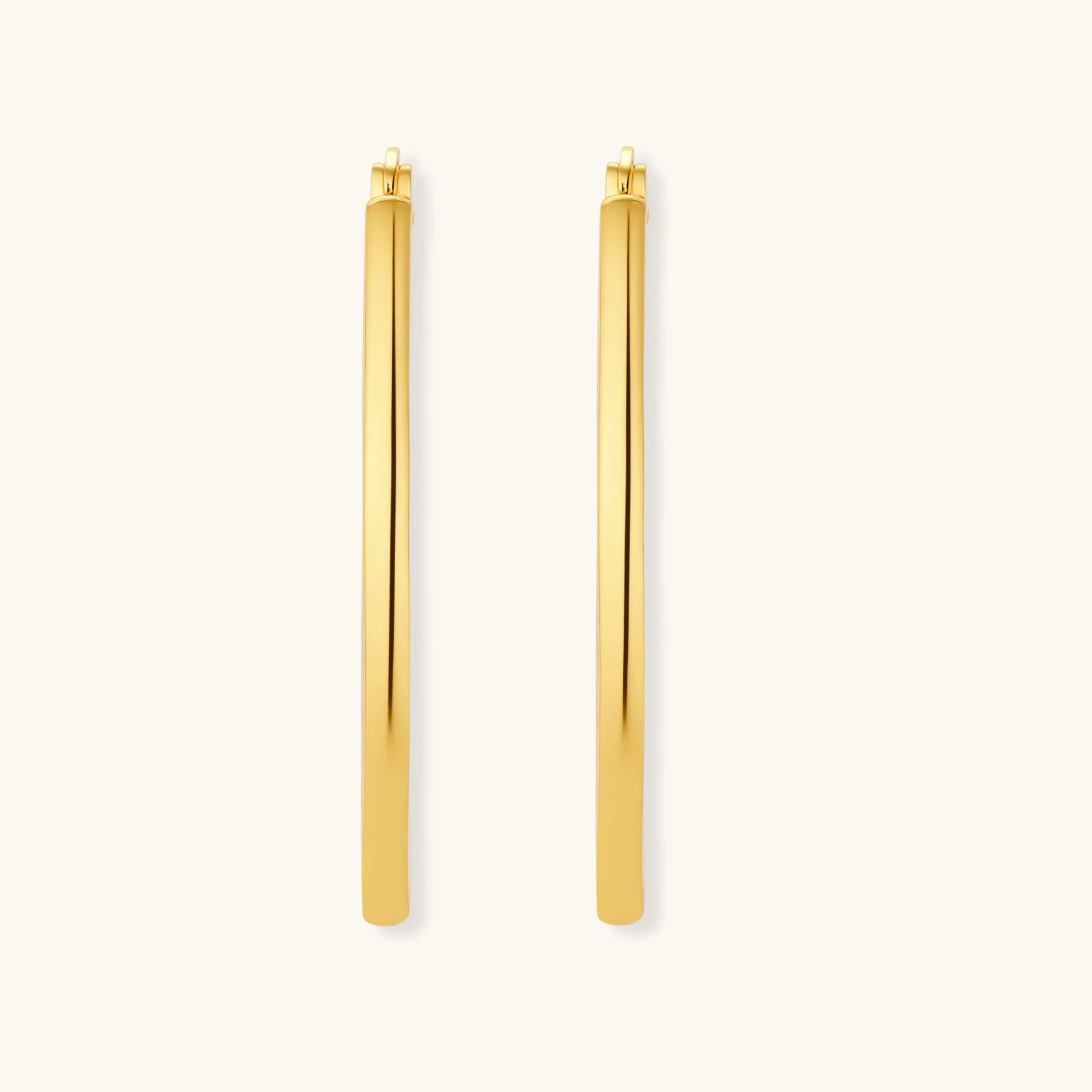 Set of geometric gold-plated sterling silver hoop earrings in oval and cushion shapes on cream background